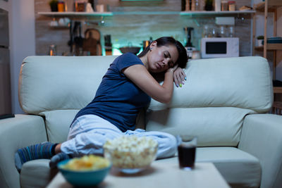 Young woman sitting on sofa at home