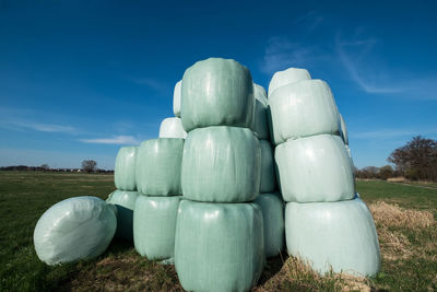 Plastic hay covers on field against sky