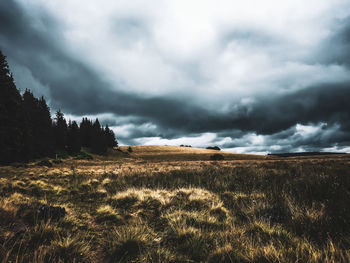 Scenic view of field against storm clouds