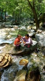 Friends sitting on rock by river