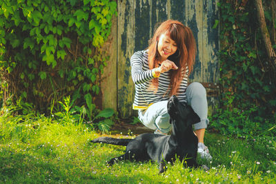  asian woman playing with her dog on the green grass in summer 