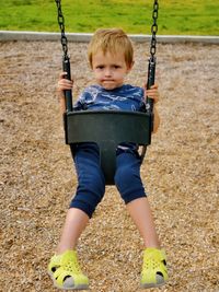 Portrait of boy on swing at playground