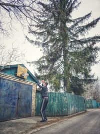 Side view of young man photographing against trees