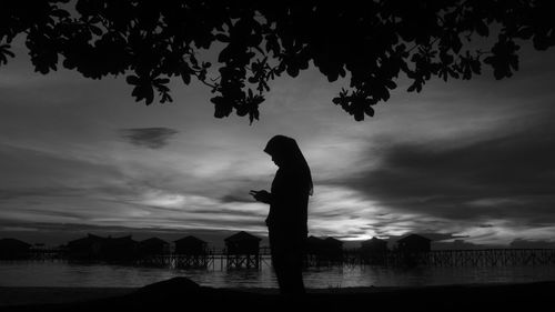 Silhouette trees by lake against sky at sunset