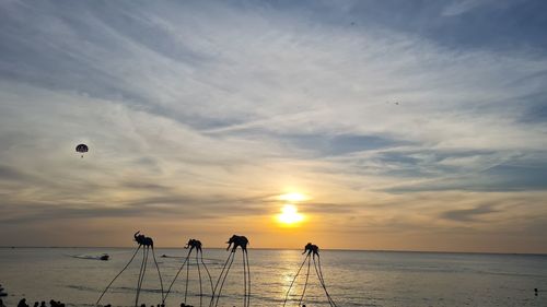 Silhouette people on beach against sky during sunset