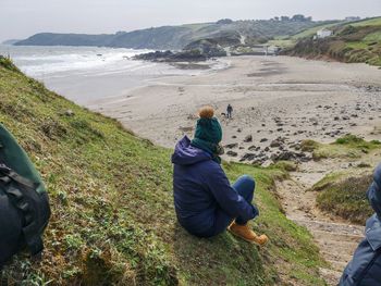 Rear view of a woman  sitting on cliff  at beach