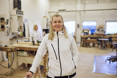 Portrait of smiling mature carpenter standing in workshop