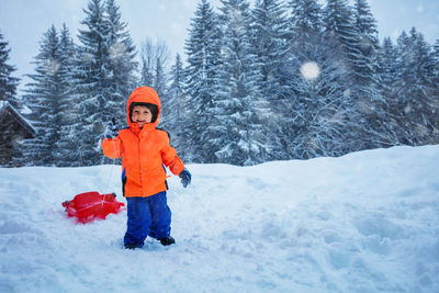 Portrait of smiling boy standing on snow covered field