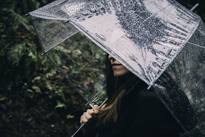 Close-up of woman holding umbrella during rain