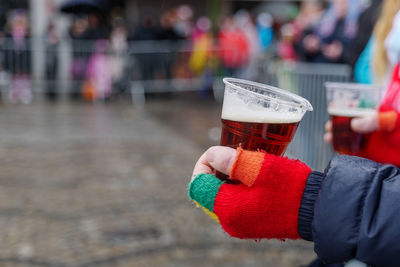 Midsection of person holding beer glass against blurred background