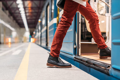 Man in black shoes, burgundy pants and white jacket enters into a subway train. transport concept.