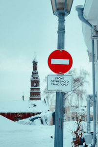 Road sign on snow against sky