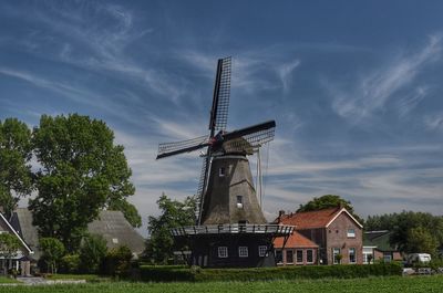Traditional windmill by building against sky