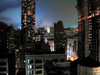 Illuminated buildings in city against sky at night