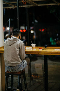 Rear view of man sitting on table at cafe