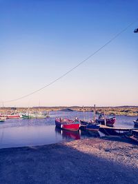 Boats moored on sea against clear sky