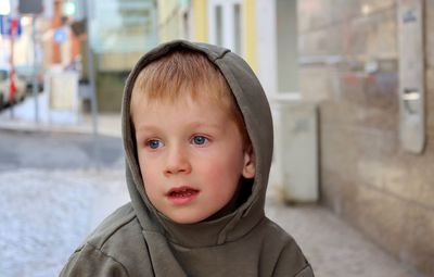 A blond boy in a hood looks dreamily into the distance. thoughtful five-year-old boy.