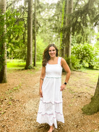 Young woman standing against trees