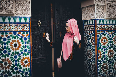 Full length of woman standing against pink wall