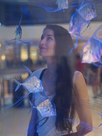 Close-up of young woman in fish tank at aquarium