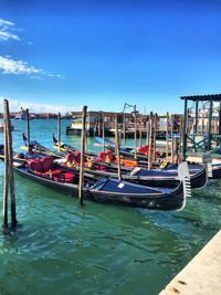 Boats moored on shore against blue sky