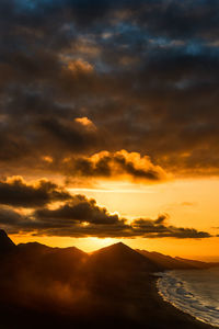 Scenic view of mountains by sea against sky during sunset