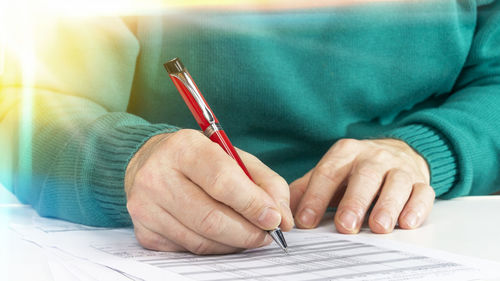 Close-up of man holding paper with book on table