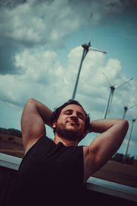 Low angle view of man looking away against sky relaxing and streching