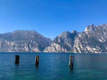 Scenic view of sea and mountains against clear blue sky