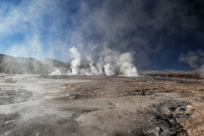 Smoke emitting from volcanic landscape against sky