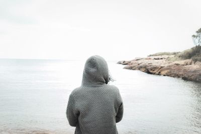 Rear view of man looking at sea against sky