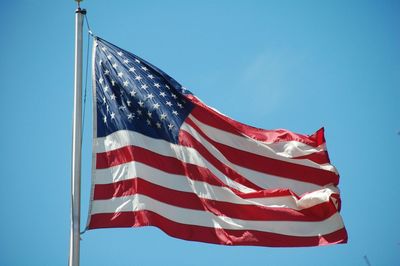 Low angle view of flag against blue sky