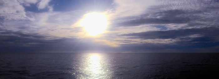 Scenic view of sea against cloudy sky at sunset