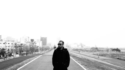 Portrait of man standing against sky in city