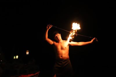 Portrait of shirtless man performing with fire at night
