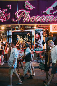 Group of people walking on illuminated street at night