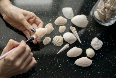 Cropped hands of woman painting seashell
