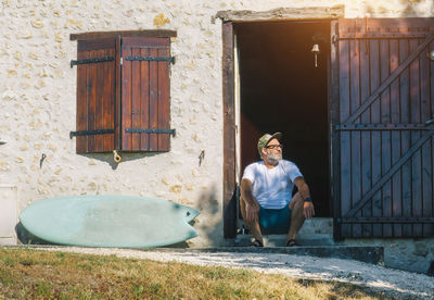 Portrait of man sitting at doorway