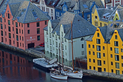 Sailboats moored on river by buildings in city