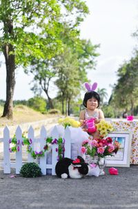 Cute baby girl with gifts and toys sitting outdoors