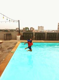 Rear view of man in swimming pool against clear sky