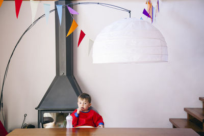 Portrait of boy sitting on table at home