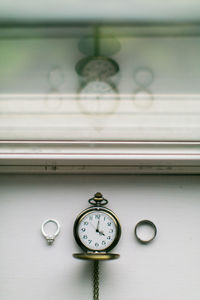 Directly above shot of pocket watch with rings in window sill