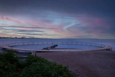 Bridge over sea against sky during sunset