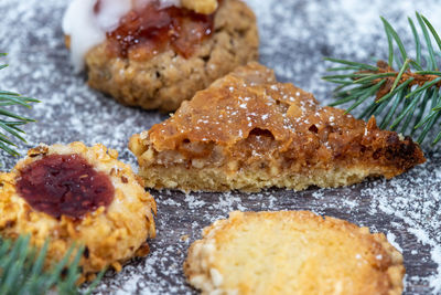 Close-up of various christmas cookies surrounded with powdered sugar and fir branches