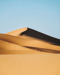 Low angle view of sand dunes against clear sky