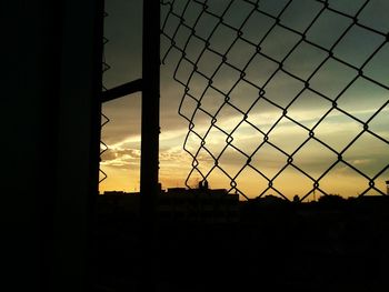 Silhouette fence against sky during sunset