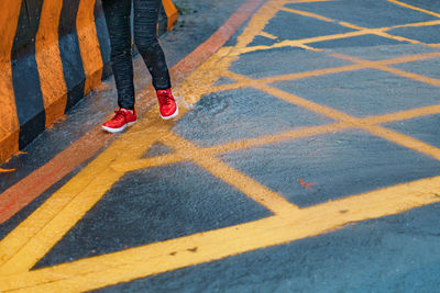 Low section of woman walking on road during rain