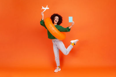 Low angle view of woman standing against orange background