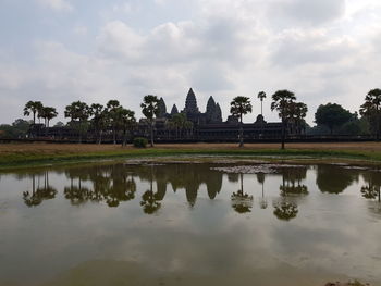 Reflection of trees and building in lake against sky